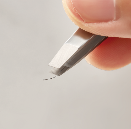 Close-up of DUROX precision slant tweezers gripping a strand of plucked hair.
